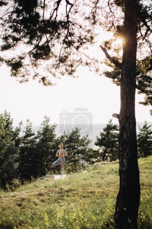 Photo for A young woman practices yoga and meditates in the mountains at sunset. Peace and unity with nature. - Royalty Free Image