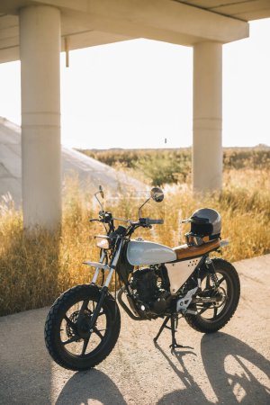 Téléchargez les photos : Une élégante moto caferacer se tient sur la route pendant le coucher du soleil. - en image libre de droit