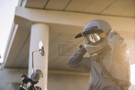 Foto de Un motociclista se pone un casco mientras está sentado en una motocicleta - Imagen libre de derechos