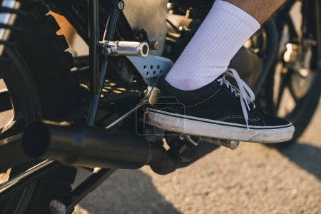 Foto de Primer plano de la pierna de un motociclista en un soporte de motocicleta. - Imagen libre de derechos