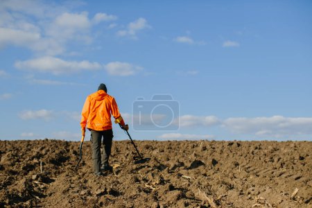 Photo for A man with an electronic metal detector in the field. Copyspace - Royalty Free Image