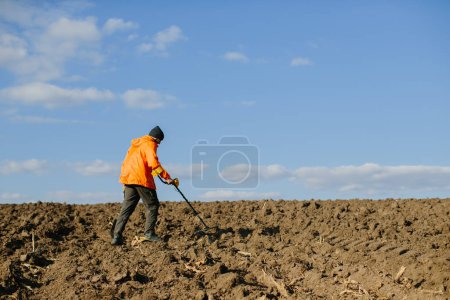 Photo for A man with an electronic metal detector in the field. Copyspace - Royalty Free Image