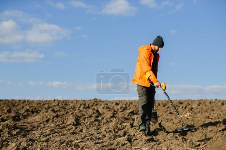 Foto de Un hombre con un detector de metales en el campo. Búsqueda de tesoros. - Imagen libre de derechos