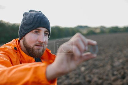 Foto de Un hombre tiene una moneda antigua en sus manos, encontrada en un campo con un detector de metales. - Imagen libre de derechos