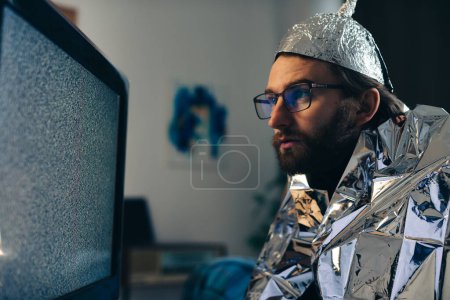 Photo for Man in Tin Foil Hat and Blanket Watching TV Interference - Royalty Free Image