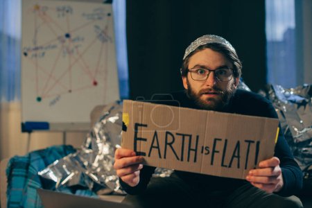 Téléchargez les photos : Favoriser la pseudoscience : l'homme tenant le signe "La Terre est plate" - en image libre de droit