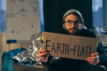 Pseudowissenschaft: Der Mensch hält das Schild "Die Erde ist flach"