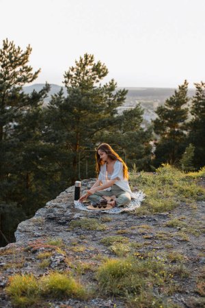 Photo for Young woman meditating sitting on a rock at sunset. - Royalty Free Image