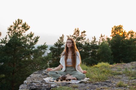 Photo for Tea ceremony in the mountains at sunset. A young woman meditates in nature. - Royalty Free Image