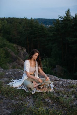 Photo for Young woman meditating with Tibetan meditation Tingsha hand bells at sunset. - Royalty Free Image
