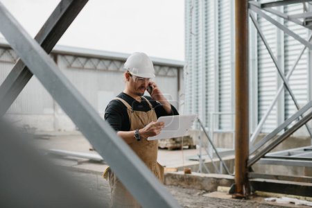 Photo for An engineer inspects the construction of grain storage silos. - Royalty Free Image