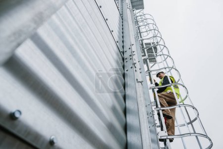 Photo for An engineer climbs the ladder on the tank for a visual inspection. - Royalty Free Image