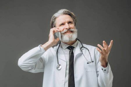 Photo for Male doctor talking on the phone, isolated on gray background. - Royalty Free Image
