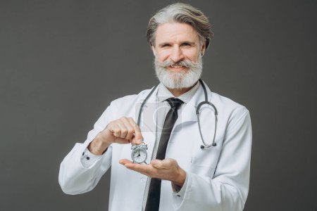 Photo for Portrait of a senior doctor with an alarm clock in his hands. The concept of healthcare and medicine. - Royalty Free Image