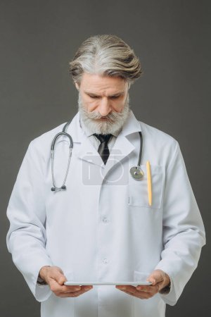 Foto de Un médico senior con una tableta en las manos. Concepto de salud y medicina. - Imagen libre de derechos