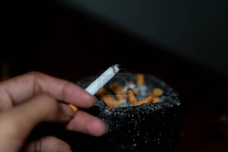 Téléchargez les photos : Cigarette en égarement sur fond noir - en image libre de droit