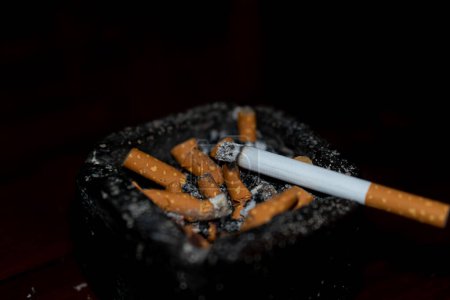 Téléchargez les photos : Cigarette en égarement sur fond noir - en image libre de droit
