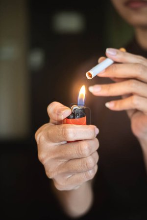 Close-up of a person lighting a cigarette with an orange lighter.