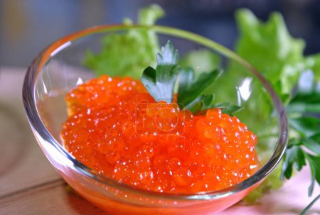 Photo for Orange Keta Chum salmon caviar in tin on crushed ice with mother of pearl spoon and toasted bread on light napkin. High quality - Royalty Free Image