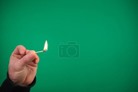 advertising Green background chromakey free space Lit matchstick held in hand by Caucasian male hand studio shot isolated. High quality photo