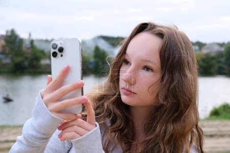 Chica joven pelirroja tomando selfie con su teléfono inteligente contra el fondo nevado. Enfoque selectivo. Foto de alta calidad