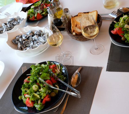 Tisch eines französischen Restaurants mit gemischtem Salat und Besteck. Hochwertiges Foto