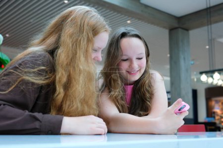 Close up of two young girls looking at smartphone playing mobile games, chatting in social media. High quality photo