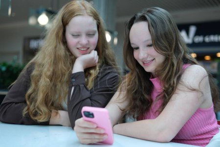 Close up of two young girls looking at smartphone playing mobile games, chatting in social media. High quality photo