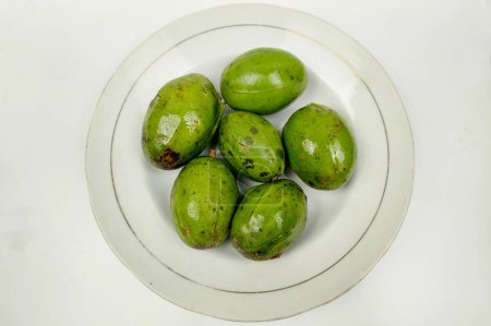 Kedondong ist auch als Ambarella-Frucht oder Othaheite-Apfel oder heiße Pflaume bekannt, die auf einem weißen Teller auf einem Holztisch köstlich schmeckt.