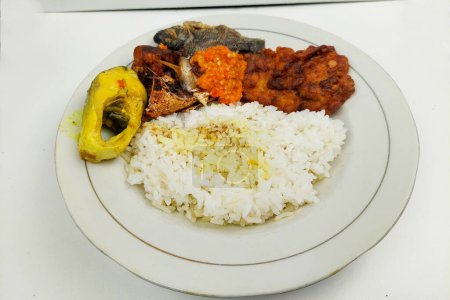 rice mixed with fried fish and tempeh vegetables on a white plate