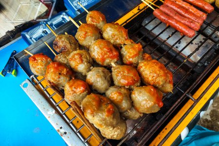 Meatballs are being grilled on a hot coal grill