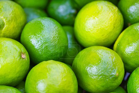 Téléchargez les photos : Limes vertes brillantes et juteuses dans un marché fermier par une journée ensoleillée : papier peint lumineux et image de fond - en image libre de droit