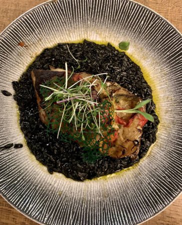 Foto de Filete de pescado con arroz negro en un plato - Imagen libre de derechos
