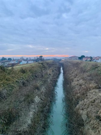 Téléchargez les photos : Magnifique paysage avec une rivière qui coule au milieu et un coucher de soleil coloré à l'horizon - en image libre de droit