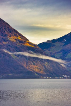 Wonderful mountains view, around the lake of Lucerne (Switzerland): the water, a cloud, the mountains and a gorgeous golden hour light