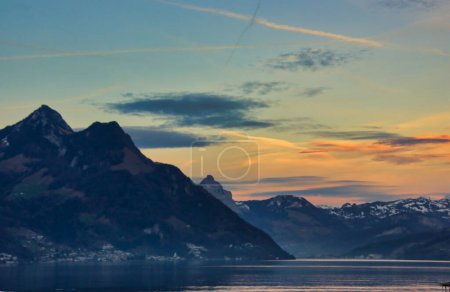 Sunset golden hour on the mountains in Switwerland: yellowm orange and blue on the water of Luzern lake in winter