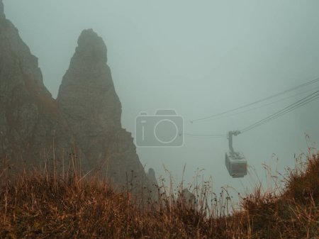 Photo for Lost in the ethereal embrace of mist, the mountains reveal their enigmatic beauty from above the veils, as the cable car navigates through this dreamy landscape. - Royalty Free Image