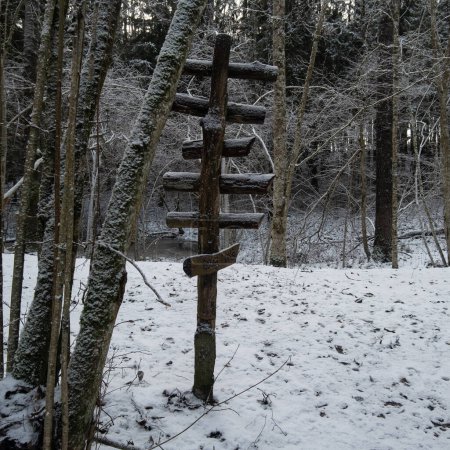 Foto de En medio del silencio cubierto de nieve, un firme letrero de madera sirve como faro en el bosque nevado de Pokainu Mezs, ofreciendo dirección en medio del abrazo invernal de la naturaleza.. - Imagen libre de derechos