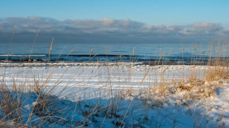 Téléchargez les photos : Une union sereine : la mer glacée rencontre les murmures dorés du crépuscule de l'hiver sur les rivages enneigés. - en image libre de droit