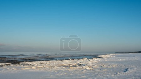 Téléchargez les photos : Au milieu du froid hivernal, la mer et la neige s'unissent sous l'étreinte chaleureuse de l'heure dorée. - en image libre de droit