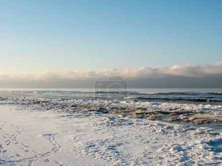 Téléchargez les photos : Un rendez-vous au crépuscule entre la côte enneigée et la mer dorée murmure des histoires d'enchantement. - en image libre de droit