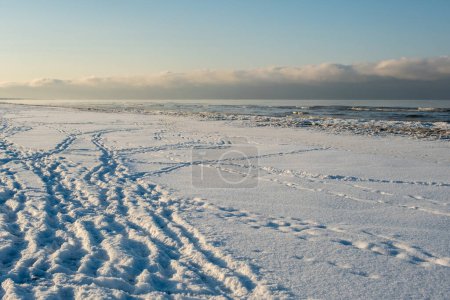 Téléchargez les photos : La côte enneigée brille d'une touche dorée alors que la lumière du jour offre son adieu hivernal. - en image libre de droit