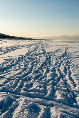 Journey's imprints captured in the golden embrace of a snow-laden coastal path
