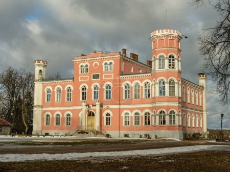 Birinu Pils in Latvia shines under the golden rays of a sunny winter day, offering a serene and picturesque landscape.