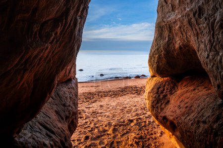 As daylight wanes, Veczemju Klintis Cave becomes a haven for sunset seekers, offering a front-row seat to nature's nightly symphony of colors on the rocky beach