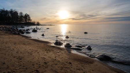 As the sun dips below the horizon, Veczemju Klintis unveils its serene beauty, with the rocky beach coast bathed in the warm hues of twilight, inviting moments of reflection and awe