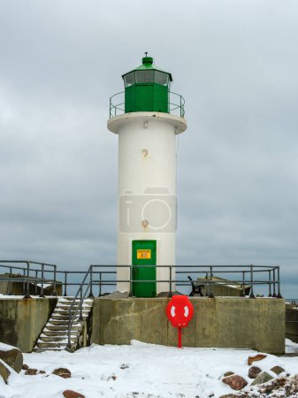 Der Leuchtturm von Ventspils steht hoch am kalten Winterhimmel und beleuchtet die verschneite Landschaft und bietet Seeleuten Trost und Orientierung inmitten der eisigen Ostsee