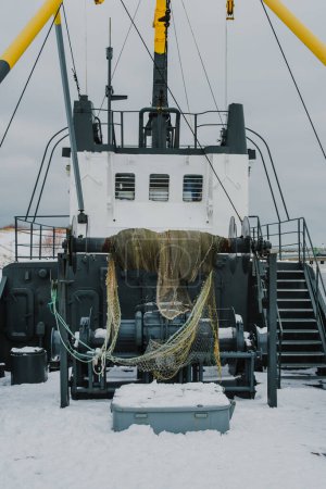 Schneebedeckte Netze und verwitterte Außenwände schmücken die Fischerboote von Ventspils, die inmitten der ruhigen Stille des Winters auf die Rückkehr wärmerer Tage warten..