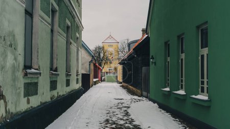 Nichée au milieu du charme tranquille de Ventspils, Latvija, une rue étroite émerge, ornée d'une fine couche de neige, invitant à l'exploration en cette journée d'hiver sereine.