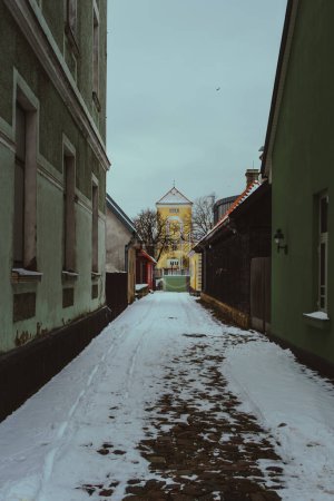 En traversant les rues étroites de Ventspils, Latvija, on trouve le réconfort au milieu du froid hivernal, tandis que l'architecture pittoresque et les sentiers enneigés peignent une scène pittoresque de solitude